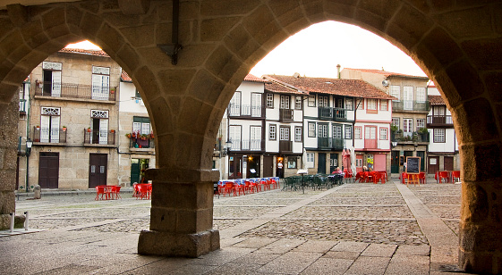S Tiago medieval town square. Guimarães, Portugal seen through stone arches. Sidewalk cafes and traditional houses.