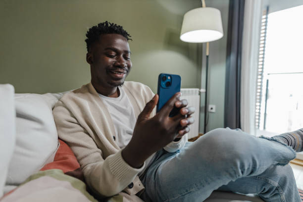 Young African-American man using mobile phone at home stock photo