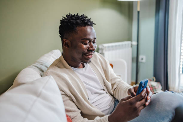 istock Young African-American man using mobile phone at home 1443886018