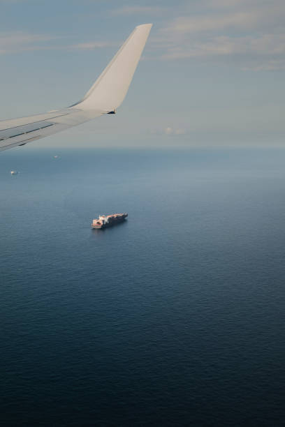 istock Freight cargo ship on a blue Sea seen from an airplane window while flying transportation scene 1443886129