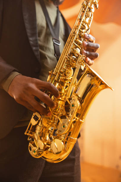 goldenes saxophon, das von einem schwarzen männlichen musiker gespielt wird - saxophonist stock-fotos und bilder