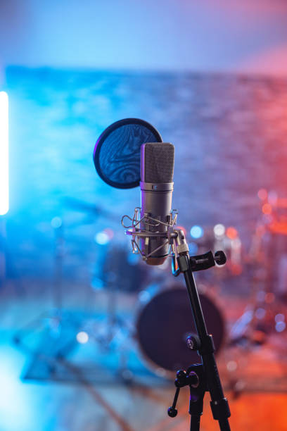 istock Mic In A Recording Studio With Drums And Lights In The Background 1443887347
