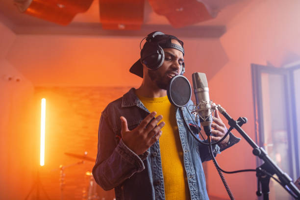 jovem adulto cantor de música masculina negra cantando apaixonadamente em um belo estúdio iluminado - rapper - fotografias e filmes do acervo