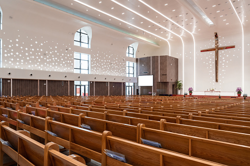 The interior of a church is shown.  There is a pulpit and a screen in front of the rows of mauve-colored pews.