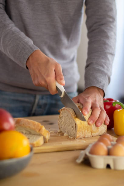 istock Close-up of mans hands cutting bread for healthy breakfast 1443890397