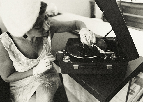 Portrait of a woman in a bar operating a gramophone.