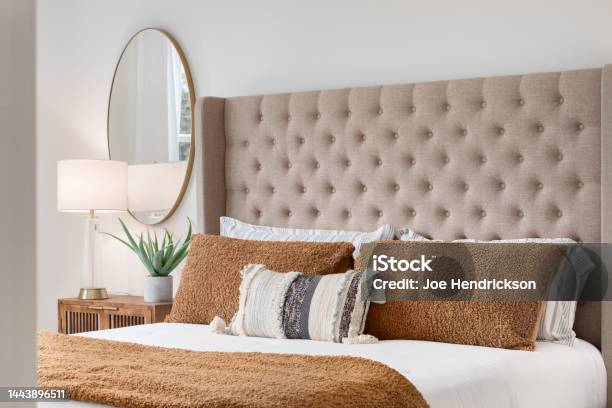 A Bedroom Detail With A Brown Headboard And Bedding Stock Photo - Download Image Now