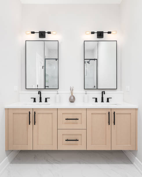 A modern bathroom with a wood floating vanity. A modern bathroom with a wooden vanity cabinet, black faucets, white marble countertop, and black rimmed square mirrors. egocentric stock pictures, royalty-free photos & images