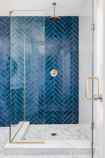 A blue herringbone shower. A blue single herringbone tiled shower in a luxury home with gold hardware. bathroom designer shower house stock pictures, royalty-free photos & images