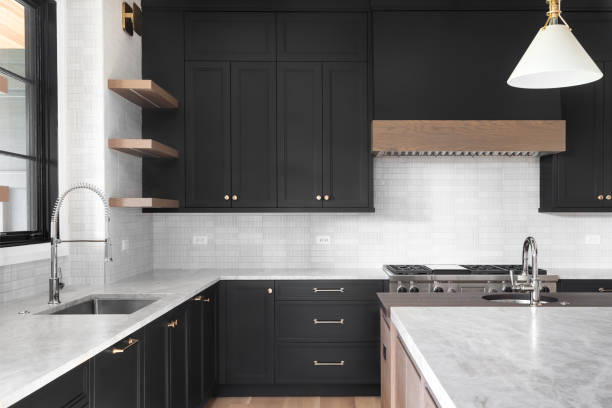 A black kitchen with stainless steel appliances. A luxury kitchen with black cabinets, granite counter top, tiled backsplash, stainless steel appliances, and chrome faucets. cupboard stock pictures, royalty-free photos & images