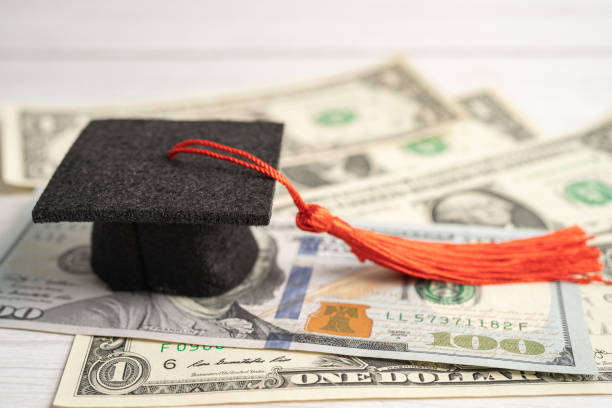 istock Graduation gap hat on US dollar banknotes money, Education study fee learning teach concept. 1443901467