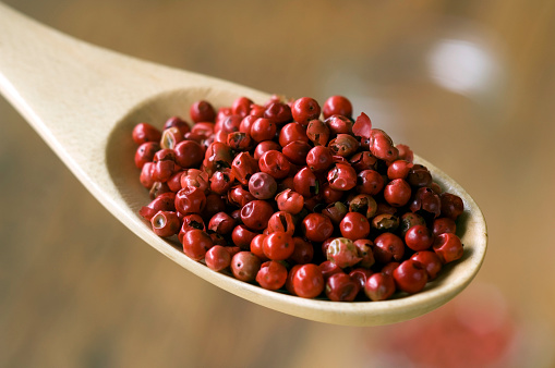Red peppercorns in a wooden spoon.