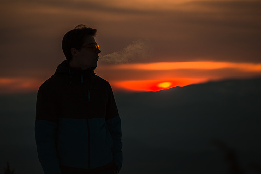 Silhouette of young man in sunset, with breath