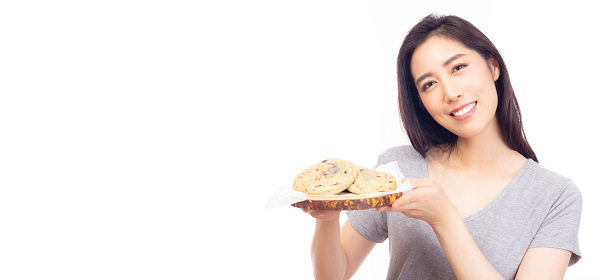 Delicious homemade chocolate chip cookies Beautiful woman holding plate of chocolate chip cookies for eating Yummy cookies putting on stencil paper isolated on white background, studio shot Copy space
