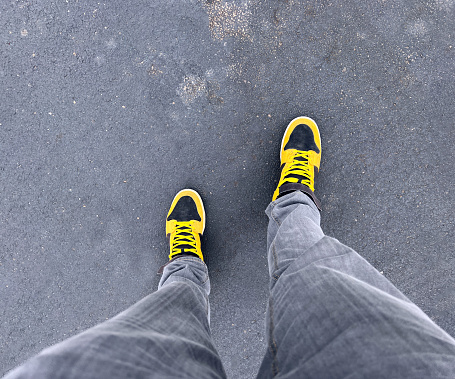 A man wearing yellow shoes on an asphalt background.