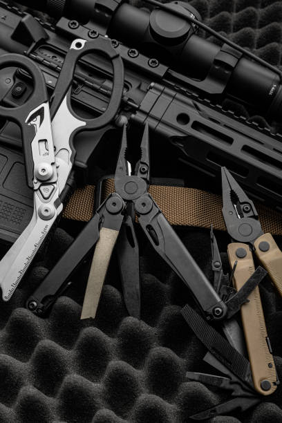 istock Modern multitool with many tools. A portable multi-tasking military tool lies next to the weapon. Multifunctional scissors. Dark background. 1443904070