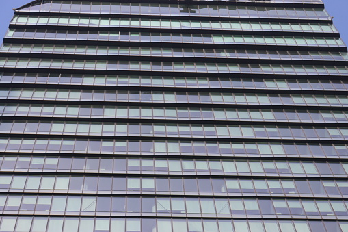 The glass facade of a modern office building in London, seen from below.