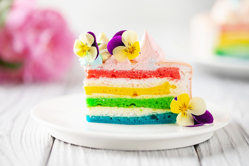 Delicious rainbow cake on plate on table on light wooden background