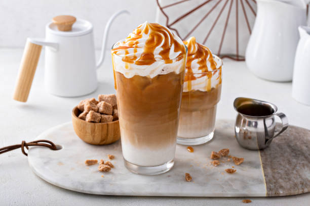 latte al caramello ghiacciato condito con panna montata e salsa al caramello - latté foto e immagini stock