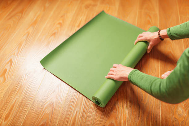 istock A woman rolls out a green mat before a yoga class 1443910691