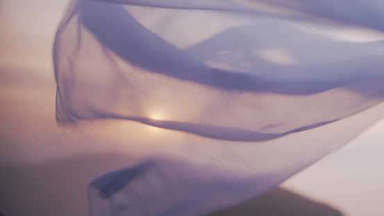 White see-through silk fabric floating and waving on the wind at sunset