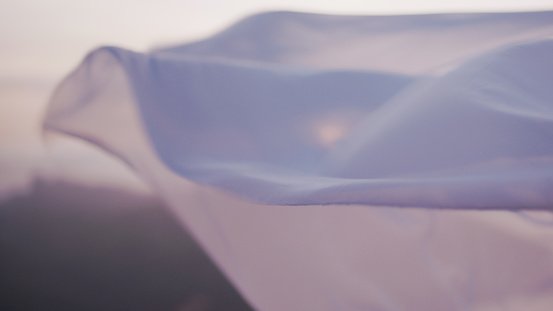 White see-through silk fabric floating and waving on the wind at sunset