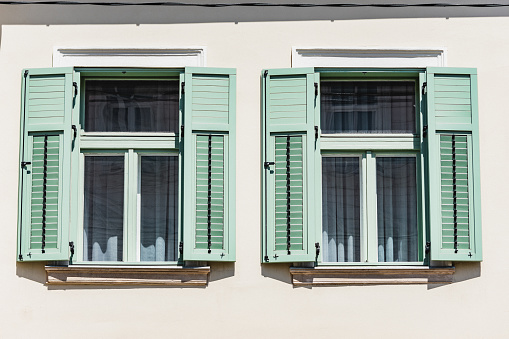 Mediterranean home with open green shutters made of wood. Retro rustic windows style