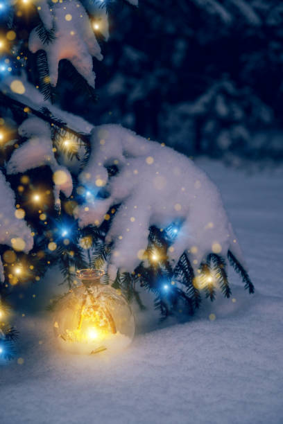 istock Christmas tree lights and a lantern under the tree. Christmas flashlight under a snowy Christmas tree in the forest 1443915396
