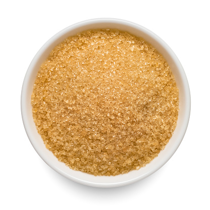 Brown sugar in white bowl isolated on white background. Top view.