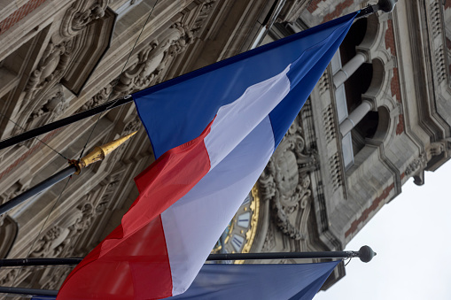 French flag at the entrance of the Chamber of Commerce in the French city of Lille on the Place du Théâtre. The building was built between 1910 and 1921 and was designed by architect Louis Marie Cordonnier; Lille, France