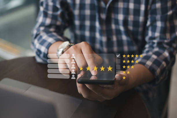 istock Man holding smartphone with five-star pop-up icon for customer service experience, feedback review satisfaction, and business satisfaction survey. 1443921104