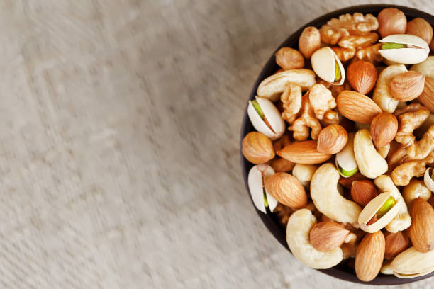 istock Assorted nuts in a plate on a wooden table with a burlap cloth. 1443922206