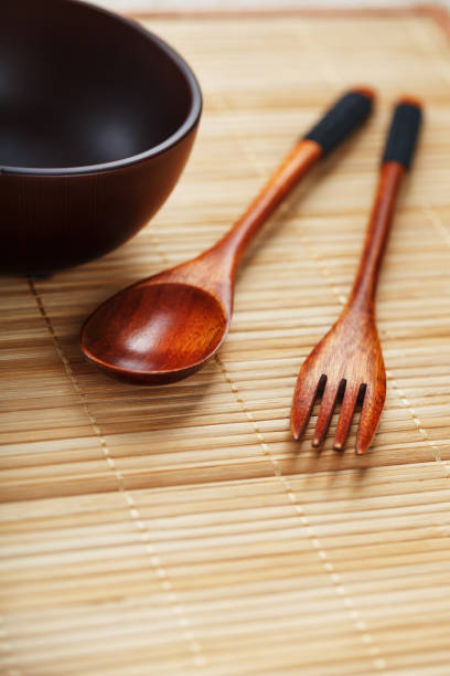istock Dark wood spoon, fork and empty cup on bamboo backing in Asia. 1443927063