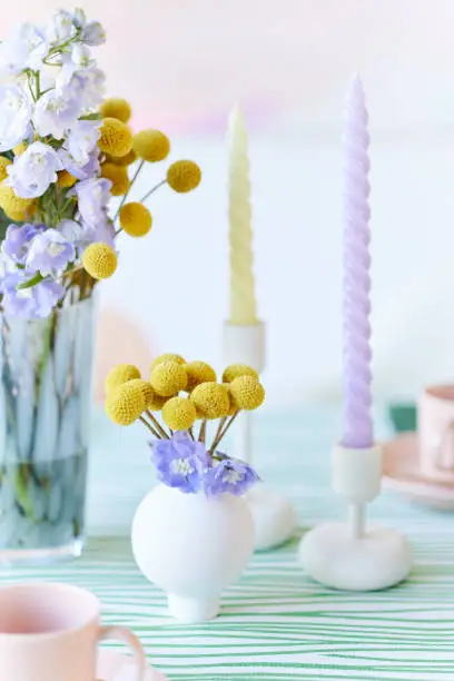 a table decoration with flower vase and candle