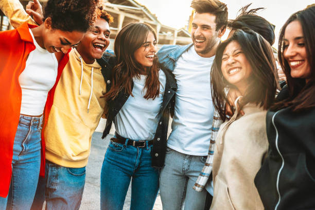 Happy multiracial young people celebrating party together outside - Group of university students having fun in college campus - Friendship concept with guys and girls hanging out on city street stock photo
