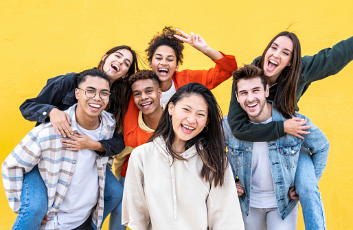 Comunidad diversa de jóvenes sonriendo juntos en un fondo de pared amarilla - Estudiantes universitarios multirraciales que se divierten riendo afuera - Concepto de cultura juvenil photo