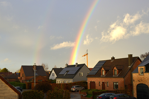 Leuven, Vlaams-Brabant, Belgium - November 23, 2022: rainbow in the sky behind the roofs of houses elevated view