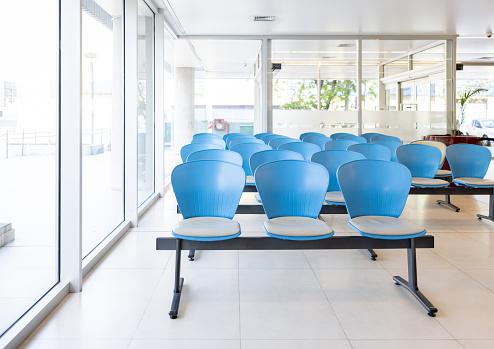 Empty waiting room at a hospital with blue chairs - healthcare and medicine concepts