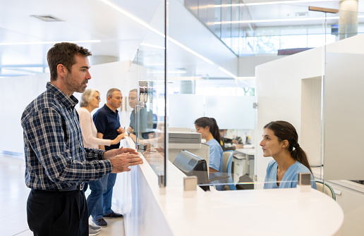 Latin American man registering at the hospital but complaining to the receptionist - healthcare and medicine concepts