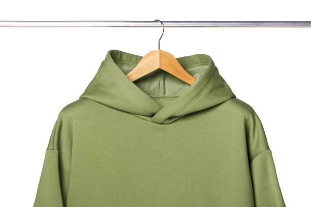 木製のハンガーの正面図にぶら下がっている緑のスウェットシャツ。モダンで快適なスポーツウェアのコンセプト。