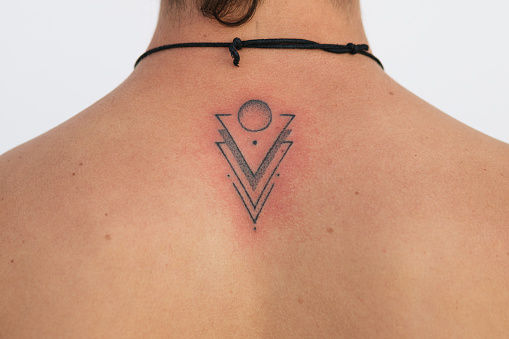 Detail of recent tattoo finished with the red skin irritation, minimalist design with dots triangles and circles