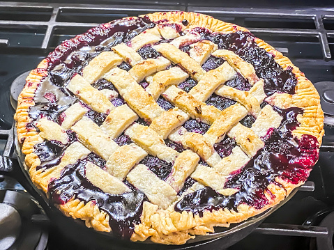 A blueberry pie with latticework sits in oven as it nears the end of baking.