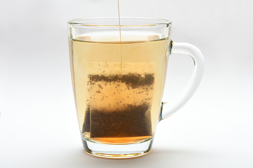 Teabag in heat water. Tea bag in a transparent tea cup on the white background