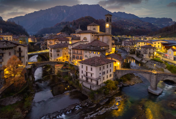 paisaje aéreo del pueblo: antigua iglesia y cruce de ríos con montañas como telón de fondo - architecture bergamo blue building exterior fotografías e imágenes de stock