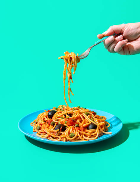 pasta puttanesca teller minimalistisch auf grünem hintergrund. vegane pasta essen. - vibrant color tomato vegetable pasta stock-fotos und bilder
