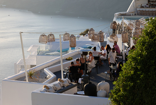 Imerovigli, Santorini, Greece - June 29, 2021: Tables on the restaurant terrace with a picturesque view of the sunset in Imerovigli. Santorini, Greece.