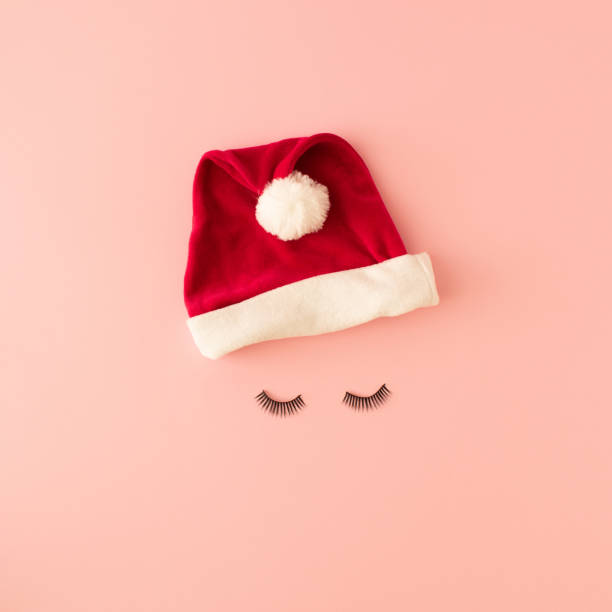 istock Santa hat and black eyelashes on pink background. Christmas concept. 1443955816