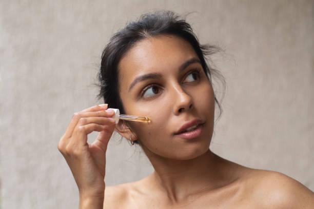 istock Young woman applying face oil 1443958163