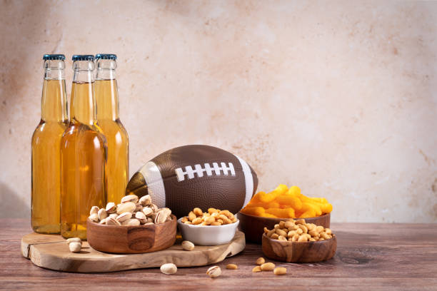 병에 담긴 맥주와 럭비 공이 있는 나무 테이블에 간식, 게임 야간 음식 - american football football food snack 뉴스 사진 이미지