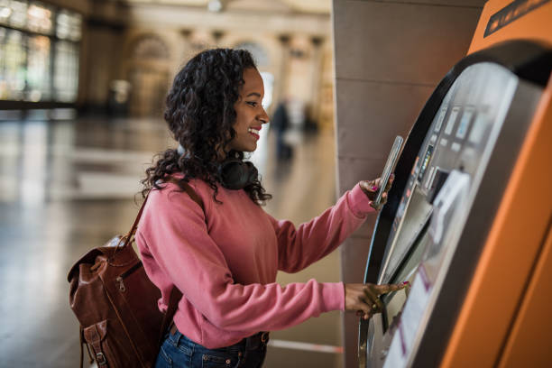 A beautiful young woman uses an ATM at a metro station in Barcelona, withdraws her money to go shopping stock photo